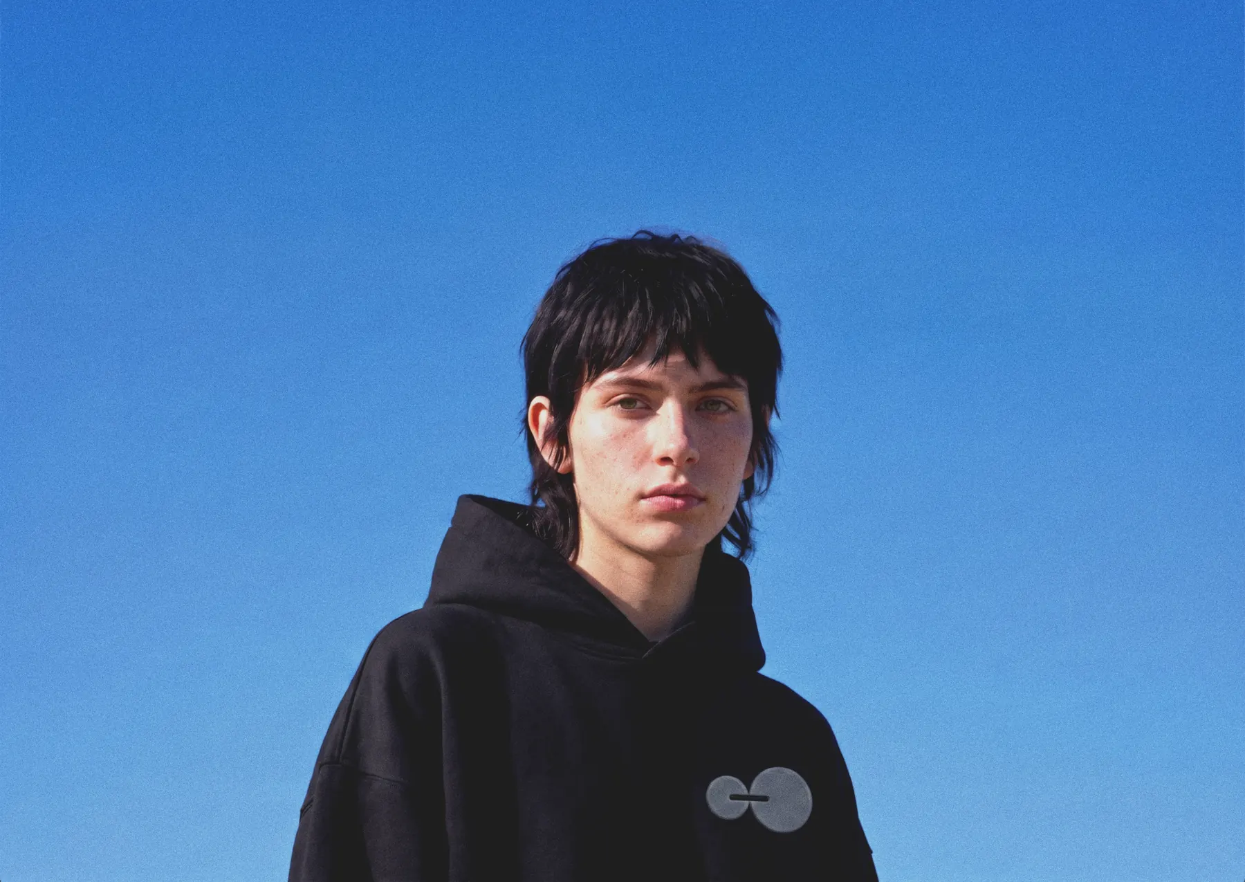 Someone in an Orbital Leap hoodie against an open blue sky